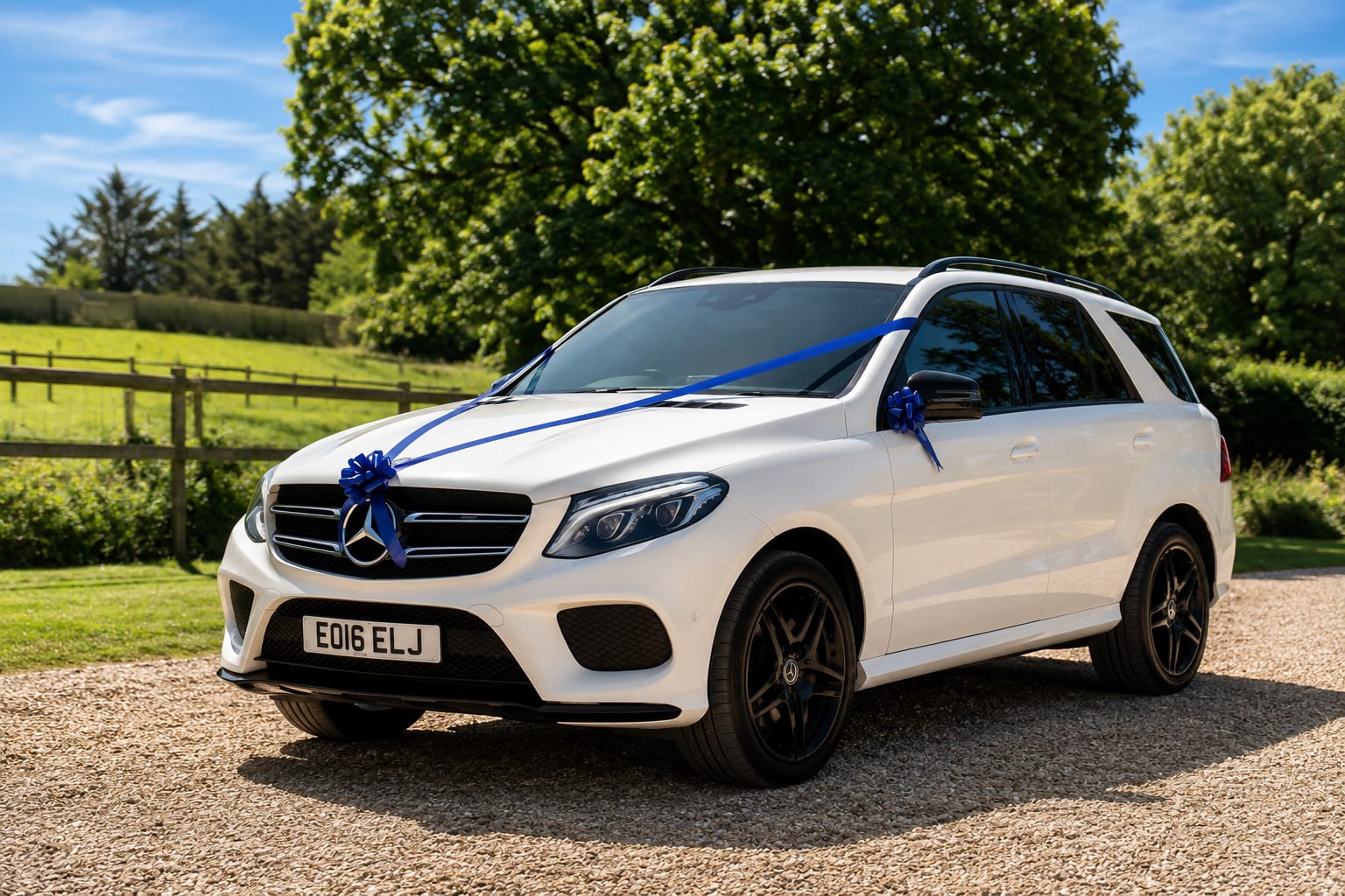 White Mercedes-Benz 4x4 dressed with ribbons, parked on a gravel drive in the countryside